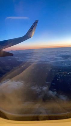 the wing of an airplane as seen from above, with clouds in the foreground