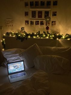 an open laptop computer sitting on top of a bed covered in white sheets and pillows