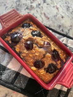 a red casserole dish filled with blueberries and oatmeal