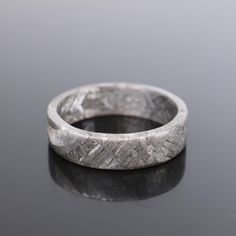 a silver ring sitting on top of a black surface