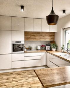 a kitchen with white cabinets and wooden counter tops next to a large window that looks out onto the outdoors