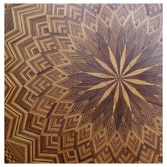 a wooden table top with an intricate design on the center and bottom part, inlaided with wood strips