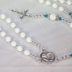 Choose your pearl and crystal color, metal finish (silver or gold), cross and connector. All of my pieces are made-to-order (custom). If you don't see what you want, convo me and we'll make it together. Rosary of 6mm and 8mm Swarovski pearls (shown with Ivory Gem) with silver bead caps capped off with 4mm Swarovski crystal bicones (shown in Light Turquoise). The beads separating the decades are 4mm silver (metal) beads. The medal (connector) shown on this listing is the current pop, Pope Francis Spiritual White Cross Jewelry, White Crucifix Necklace For Jewelry Making, Nickel-free White Cross Jewelry, Handmade White Crucifix Jewelry, White Spiritual Crucifix Jewelry, Spiritual White Crucifix Jewelry, White Cross Jewelry With Miraculous Medal, Silver Beaded Crucifix Jewelry, White Sterling Silver Jewelry With Spacer Beads