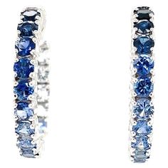 Beauty, luxury and sophistication are epitomized in this pair of elegant ombre sapphire hoop earrings featuring a stunning, unusual collection of blue and white sapphires. Over 4 carats of brilliant sapphires blending seamlessly from light to rich royal blue, bringing these 14k white gold "inside out" hoop earrings to life. Earrings measure 1 inch in diameter and have a secure and comfortable hinged safety closure. The perfect size for daytime and evening wear, casual and special occasions, these earrings are a beautifully original version of a timeless classic! Matching bracelet (BR-430) sold separately 32 round sapphires, 3.00mm, 4.26 carats total Sapphire Hoop Earrings, Earring Video, London Blue Topaz Earrings, Gold Diamond Hoop Earrings, Sapphire And Diamond Earrings, White Gold Hoops, Round Sapphire, Azul Real, Blue Topaz Earrings