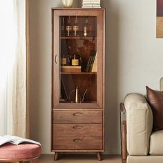 a tall wooden cabinet sitting next to a couch