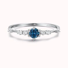 a white gold ring with a blue diamond and three diamonds on the band, set in 18k white gold