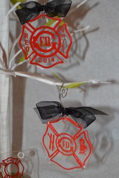 three fire department ornaments hanging from a tree