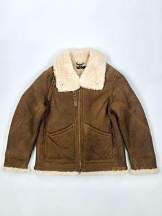 Recalling the vintage-inspired style of a classic aviator jacket, this plush iteration is constructed from curly shearling sourced from Italy and is accented with antiqued brass-tone hardware. Straight fit. Intended to hit below the hip. Shearling spread collar. Snapped collar points. Full-zip front. Two front waist patch pockets. Buckled leather tabs at the collar. Buckled leather side tabs at the hem. Shell: shearling. Trim: leather. Dry clean by a leather specialist. Due to the natural charac Sheepskin Aviator Outerwear With Padded Collar, Sheepskin Aviator Jacket With Faux Fur Lining, Rugged Sheepskin Outerwear With Faux Fur Lining, Vintage Shearling Leather Jacket With Faux Fur Lining, Shearling Aviator Fur Coat With Faux Fur Lining, Aviator Shearling Fur Coat With Faux Fur Lining, Vintage Leather Jacket With Faux Fur Lining, Classic Shearling Aviator Outerwear, Classic Aviator Shearling Outerwear