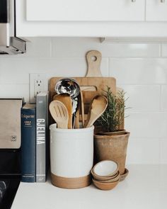 kitchen utensils and wooden spoons are on the counter