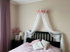 a bed with pink sheets and white curtains