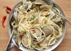 a pan filled with pasta and clams on top of a wooden table