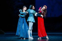 three ballerinas dressed in blue and red dance on stage