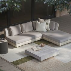 a living room with a couch, coffee table and rug on the floor in front of windows