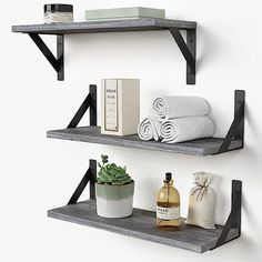 two white shelves with towels and other items on them, one shelf is black metal