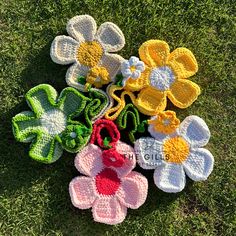 several crocheted flowers laying on the grass