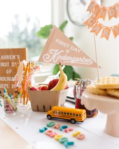 a table topped with fruit and pastries next to a sign