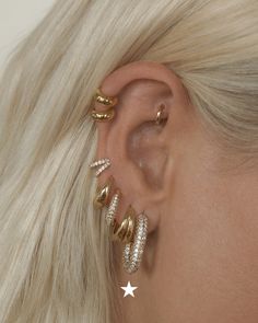 a woman with blonde hair wearing three different ear piercings