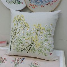 two embroidered pillows with flowers on them next to some other embroiderys and fabric items