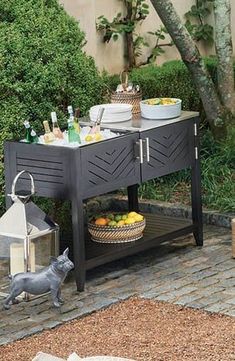 an outdoor table with food and drinks on it in the middle of a garden area