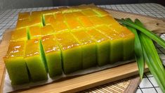 a wooden cutting board topped with slices of cake next to green onions and celery