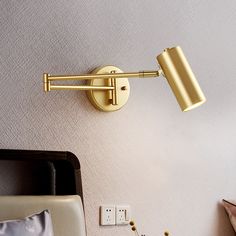 a wall light that is on the side of a wall next to a bed and pillows