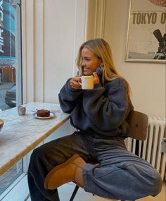 a woman sitting at a table drinking coffee