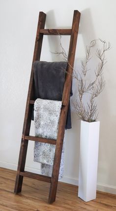 a wooden ladder leaning against a wall next to a white vase