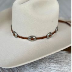 This hat band is made with brown leather that is laced through silver oval conchos. It is adjustable in the back with a metal slide. Made in the USA 1 1/8" x 7/8" conchos Genuine leather *This product is for 1 single hat band. Hat not included. Western Concho Hat Bands For Country Events, Country Style Concho Hat Band For Rodeo, Western Concho Hat Bands For Rodeo, Western Hat Bands With Concho For Curved Brim, Southwestern Concho Hat For Rodeo, Southwestern Style Concho Hat For Rodeo, Adjustable Concho Jewelry For Rodeo, Western Silver Hat Bands For Festivals, Silver Western Hat Bands For Festival