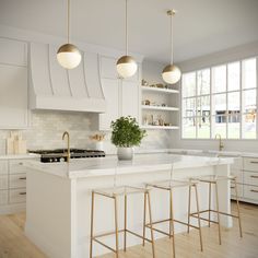 a large kitchen with white cabinets and gold bar stools next to an island in the middle