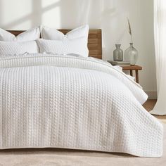 a bed with white comforter and pillows in a room