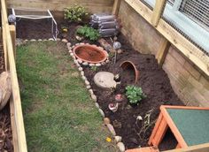 an outdoor garden with plants and rocks in the ground, next to a wooden fence