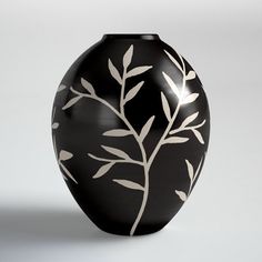 a black vase with white leaves on it