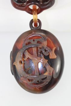 This locket is from the 1890's and it has an initial emblem on the front.  It appears to be S,T,C in script and it is lovely.  There are some scratches on the locket but none that distract from the beauty of this piece. The locket when opened has a glass front for your memories and it is 1 3/4" x 1 1/2" and weights in at 54.0 grams.  The chain is all tortoise links and measures 23" long and it has a fish hook closure all in Tortoise shell. Tortoise shell is endangered so anything before the 1973 is salesable but after 1973 it is prohibited.  This took place in 1973 because the Hawksbill Turtle was almost to extinction and in order to save them this ban went into place. Victorian Brown Collectible Jewelry, Victorian Style Brown Collectible Jewelry, Victorian Oval Jewelry With Initials, Antique Brown Carved Jewelry, Victorian Oval Brown Jewelry, Victorian Style Oval Brown Jewelry, Victorian Brown Oval Jewelry, Brown Oval Victorian Jewelry, Vintage Engraved Brown Jewelry