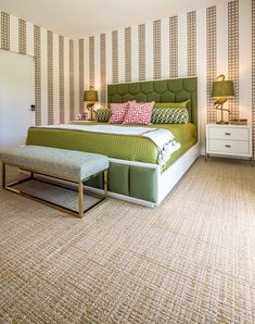 a bedroom with green and white bedding, two nightstands and a bench in front of the bed