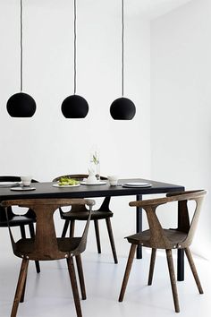 a dining table with four chairs and three lights hanging from it's ceiling above