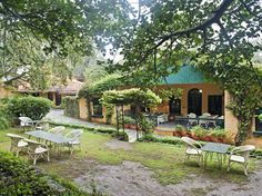 an outdoor dining area with tables and chairs in the foreground, surrounded by greenery