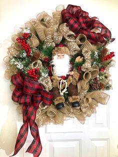 a christmas wreath hanging on the front door with a santa clause and red plaid ribbon