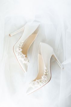 two pairs of white shoes with pearls on the toes and one pair of high heeled shoes