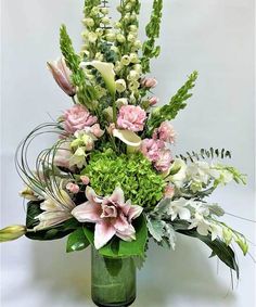 a vase filled with lots of flowers and greenery