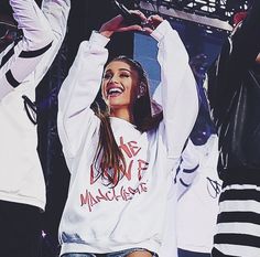 a woman standing on stage with her arms up in the air and two other people behind her