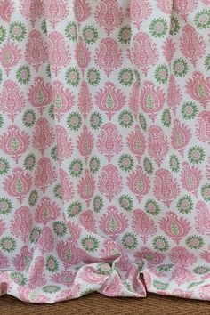 a pink and green paisley print curtain hanging from a window