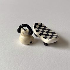 two small ceramic figurines sitting next to each other on a white table top