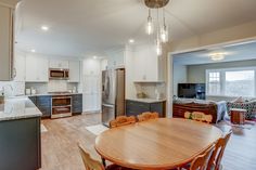 Kitchen remodel with white upper cabinets, a grey backsplash, light granite countertops, new vinyl plank flooring, and farm sink under the bay window