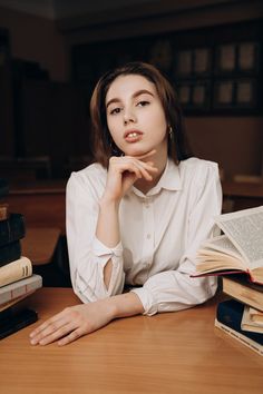 a woman sitting at a table with books and an open book in front of her