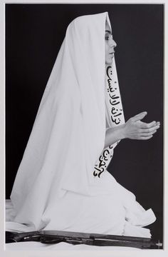 a black and white photo of a woman with a veil on her head sitting down