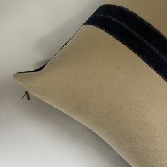 a close up of a pillow on a white surface with black and tan trimming