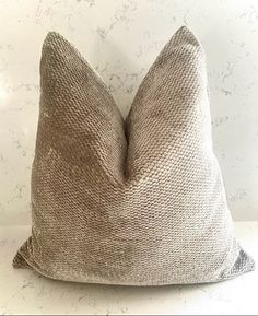 a gray pillow sitting on top of a white table