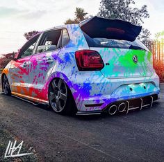 the rear end of a colorful car parked in a parking lot