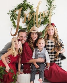 a family posing for a photo in front of a christmas sign