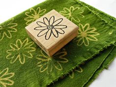 a wooden block with a flower on it sitting on top of green carpeted area